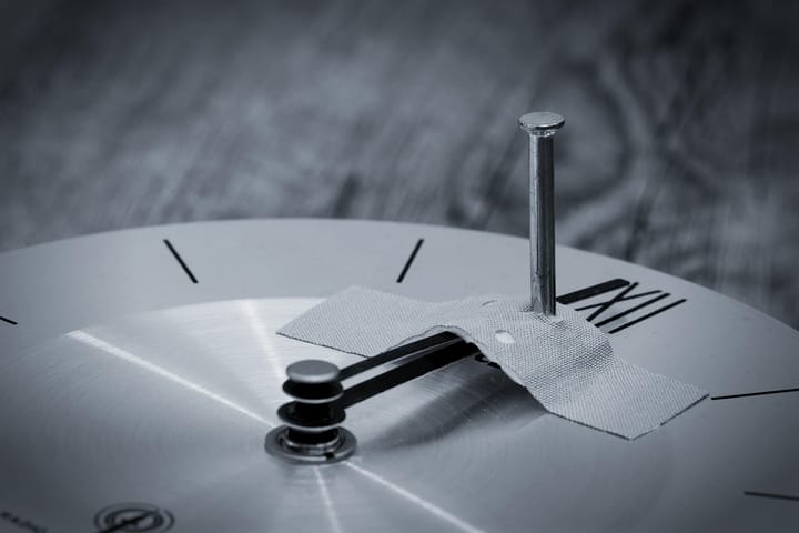 a gray dark clock has the hands spiked and taped in place.